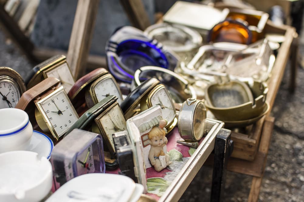 Marché d’antiquités avec horloges, vaisselle et objets vintage à trier et valoriser.